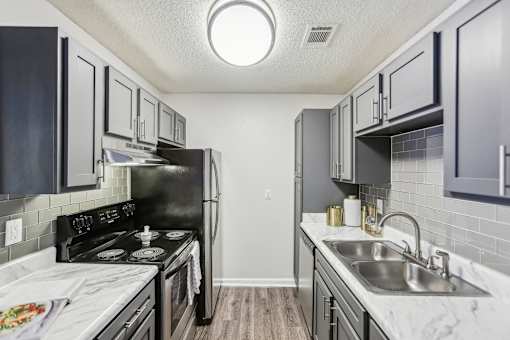 A kitchen with a black stove top oven and a black refrigerator.