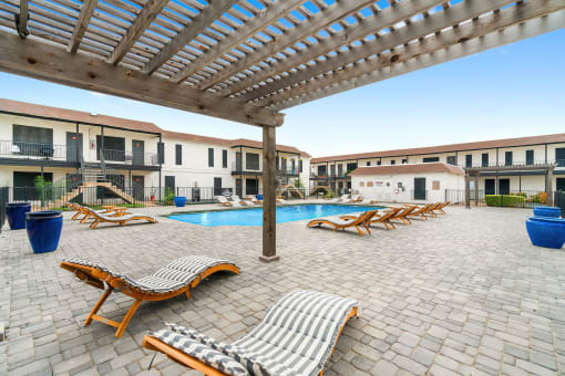 a resort style pool with lounge chairs and a pergola