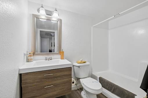 A white bathroom with a toilet, sink, and mirror.