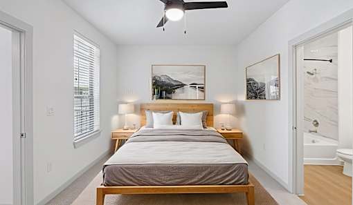 A bedroom with a bed, two lamps, and a painting on the wall.