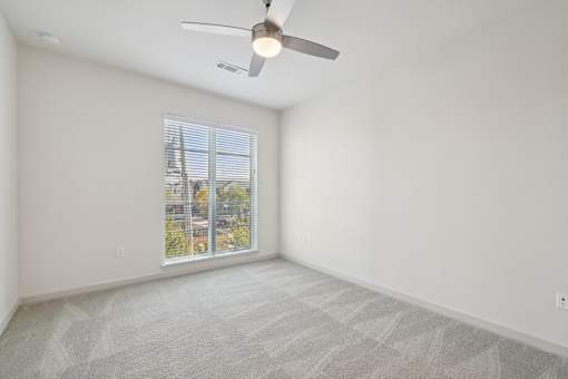 A room with a ceiling fan and carpeted floor.