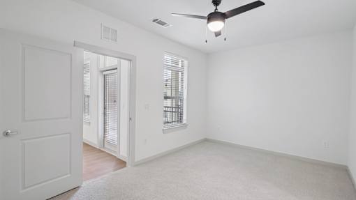 A room with a ceiling fan and a window with blinds.