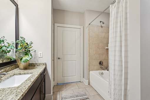 A bathroom with a white door, a white tub, and a white shower curtain.