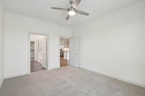 A room with a ceiling fan and carpeted floor.