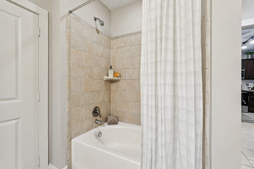 A white bathroom with a tub, shower, and a white door.