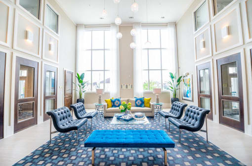 a living room with blue furniture and tall windows