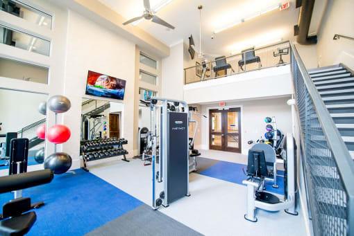 a gym with weights and cardio machines and a staircase