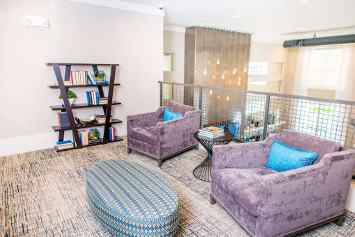 a living room with purple chairs and a book shelf