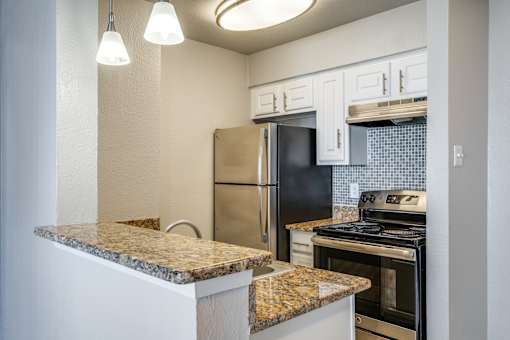 A kitchen with granite countertops and black appliances.