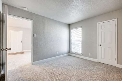 A room with a carpeted floor and two doors.