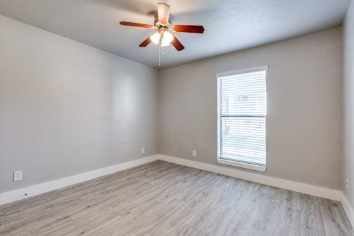 A room with a ceiling fan and a window with blinds.