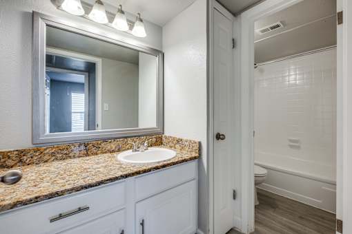 A bathroom with a sink, mirror, and bathtub.