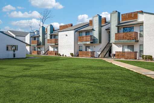 A row of modern apartment buildings with a green lawn in the foreground.