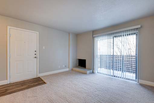 A room with a door, a window with blinds, and a fireplace.