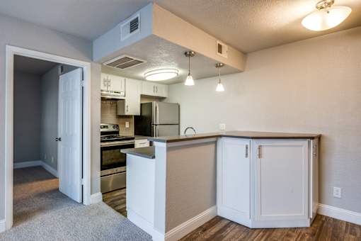 A kitchen with white cabinets and a wooden floor.