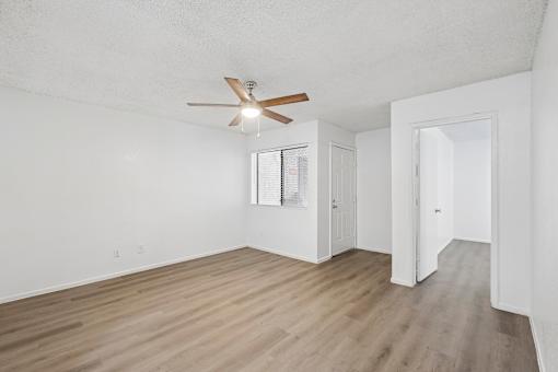 A room with a ceiling fan and wooden flooring.