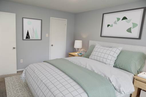 A bedroom with a bed, nightstand, and two framed pictures on the wall.