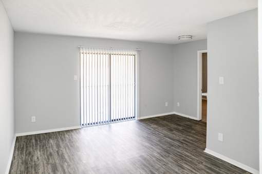 A room with a window covered by blinds and a wooden floor.