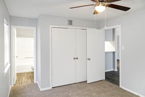 A room with a ceiling fan and three white doors.
