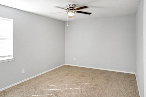 A room with a ceiling fan and carpeted floor.