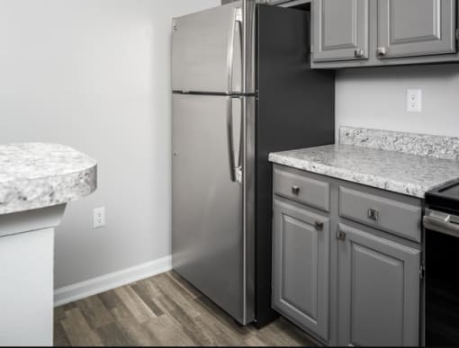 a kitchen with gray cabinets and a stainless steel refrigerator