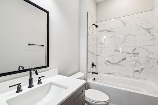 A white sink with a black mirror above it.