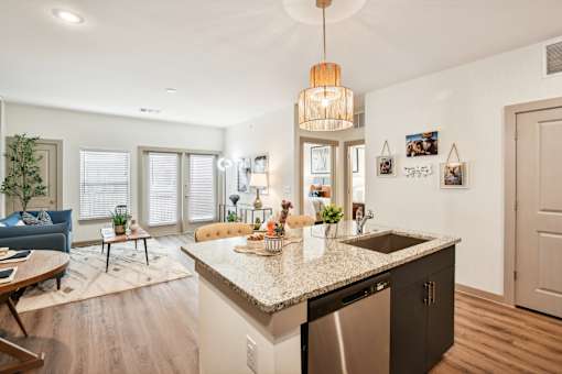 A kitchen with a granite countertop and a blue sofa in the living room.