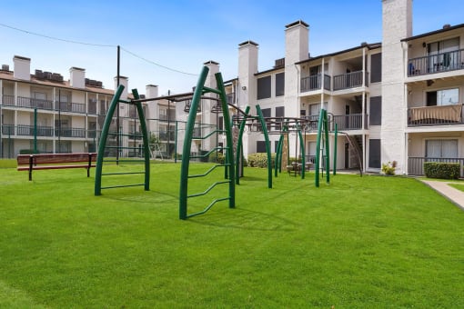 a playground with a monkey bars swing set in front of an apartment building
