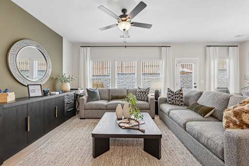 A living room with a grey couch, a coffee table, and a ceiling fan.