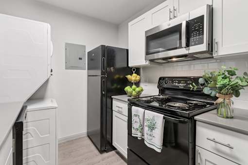 A kitchen with black appliances and white cabinets.