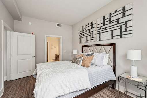 A bedroom with a large bed and a painting on the wall.
