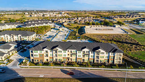 A large apartment complex with a parking lot in front.