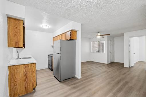A kitchen with a refrigerator, sink, and wooden cabinets.