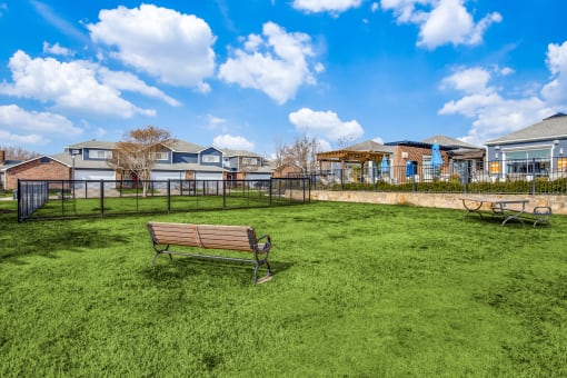 a park bench sitting in the grass in front of a playground