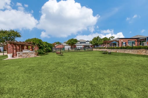 the backyard of a house with a large lawn and a stone wall