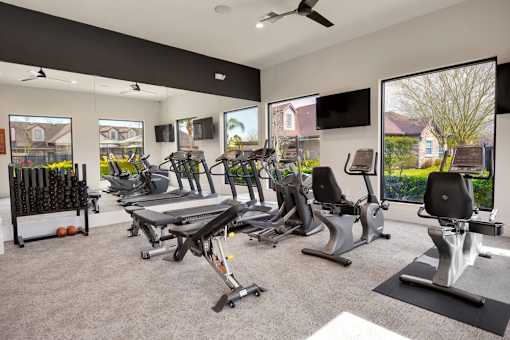 A gym with treadmills, exercise bikes, and a television.