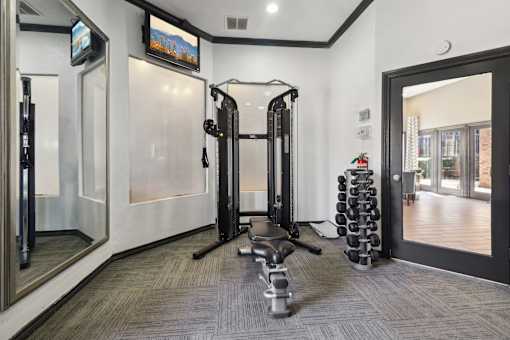 A gym with a row of treadmills and a television mounted on the wall.