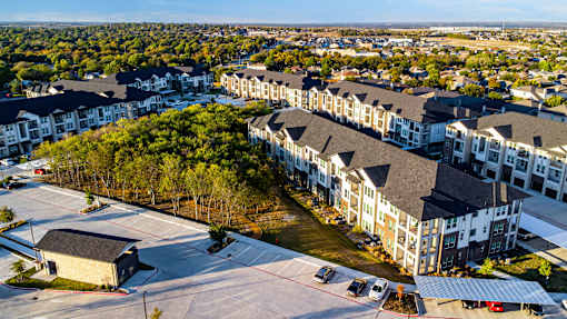 A large apartment complex with a parking lot in front.