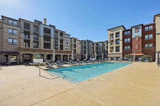 A large swimming pool is surrounded by apartment buildings.