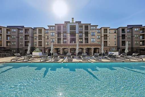 A large swimming pool in front of apartment buildings.