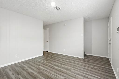 A room with wooden flooring and white walls.