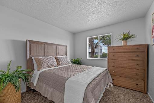 A bedroom with a bed, dresser, and window.