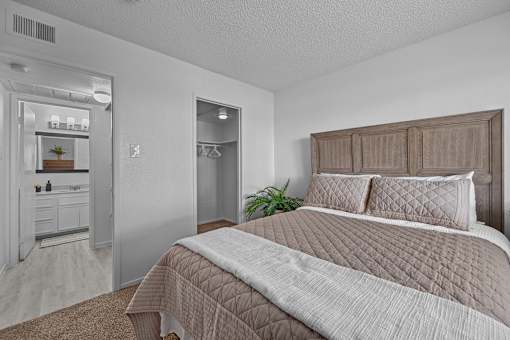 A bedroom with a large bed and a mirrored closet.