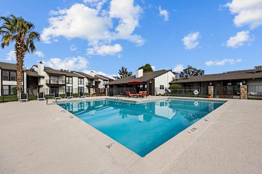 A large swimming pool in front of a building with a palm tree.
