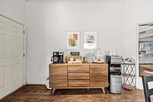 A white wall with a wooden cabinet and a fridge in the corner.
