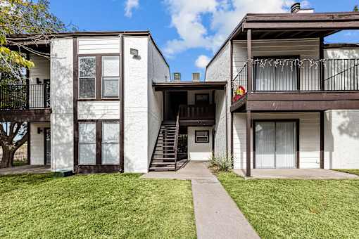 A white two-story house with a balcony on the upper floor.