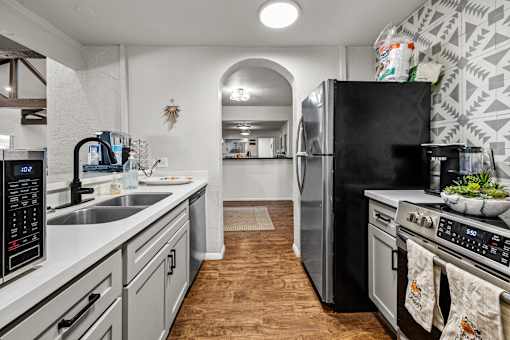 A kitchen with a black fridge and stove top oven.