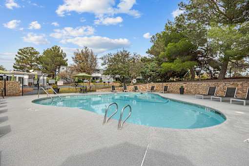 A swimming pool surrounded by trees and a stone wall.