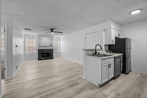 an empty living room with a kitchen with a stove and refrigerator