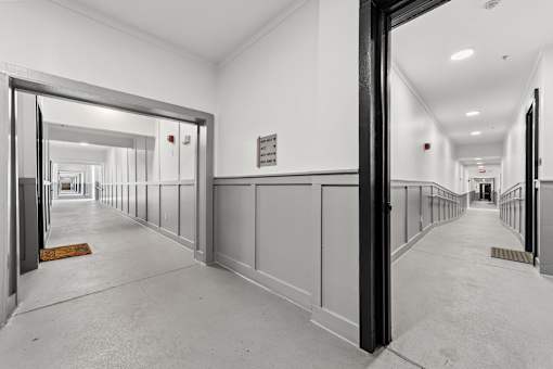 A long hallway with white walls and a white floor.